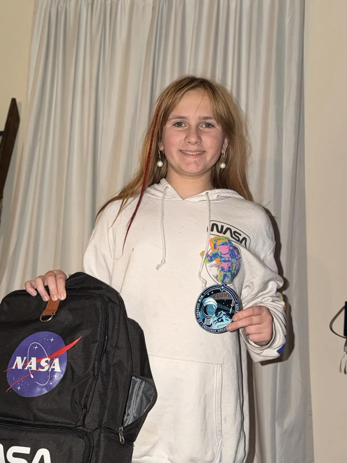 Kenzie Edwards holding a TESA mission patch and NASA backpack, ready for Space Camp